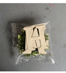 Detail of wooden HOME letters and green wreath wall decor in transparent packaging