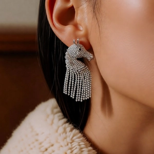 Close-up of model wearing silver tassel earrings with crystal horse head detail