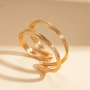 Detail of multi-layer golden wire wrap cuff bracelet with geometric twisted design