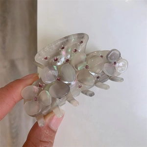 Close-up of a mint green acetate hair claw clip decorated with pink rhinestone flowers