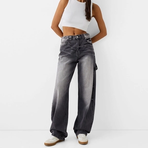 Détail d'un jean taille haute à jambe large avec texture délavée vintage et moustaches