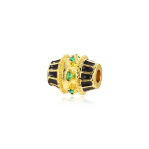Detail of a gold-plated oval bead with black enamel stripes and green marquise gems