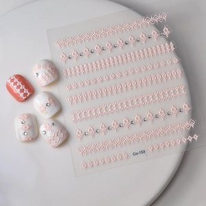 Detailed view of pink lace embossed nail stickers with rhinestones on a white plate