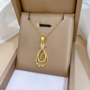 Détail du collier MAMA doré en forme de goutte avec zircons dans son écrin à bijoux