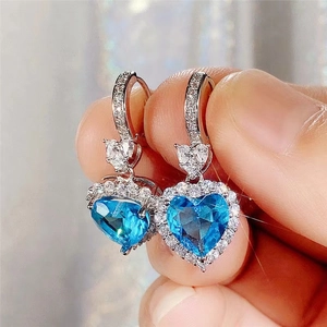 Close-up of heart-shaped blue topaz earrings with sparkling zircon micro-pave details