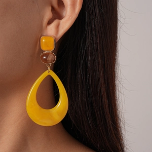 Retro geometric resin earrings featuring yellow square and drop shapes on a model