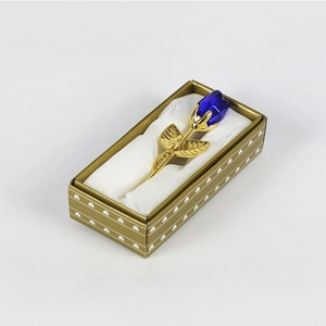 Détail d'une rose en cristal bleu à tige dorée dans son coffret cadeau à motifs cœurs