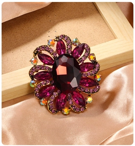 Detailed macro view of purple crystal floral brooch with golden metal base on silk