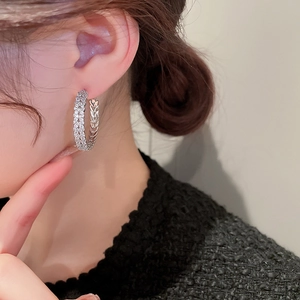 Close-up of sparkling silver zircon circle hoop earrings worn on female model's ear