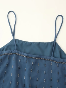 Detail of blue chiffon top showing silver beading craftsmanship and neckline texture