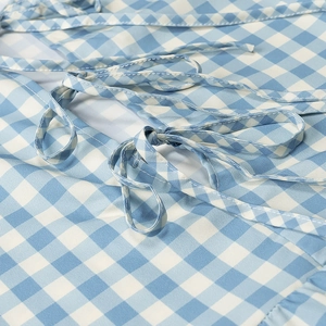 Detail of light blue gingham fabric showing the tie-up ribbon and ruffle hem design