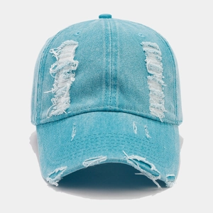Détail d'une casquette en denim bleu clair avec des bords effilochés et un aspect usé