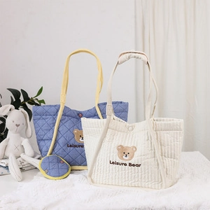 Bolsos tote de lona acolchada en beige y azul con bordado de cabeza de osito