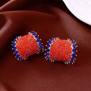 Vintage gold-plated C-shaped earrings with red and blue pave rhinestones on brown silk