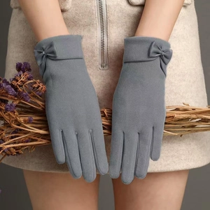 Detail of grey winter gloves for women with decorative bow and soft plush fleece material