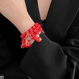 Détail d'un bracelet multicouche en perles rouges avec breloques chat de la fortune