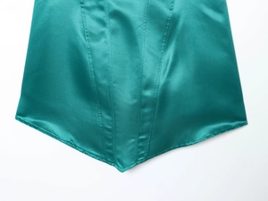 Dettaglio dell'abito in raso verde smeraldo con cuciture raffinate e trama liscia
