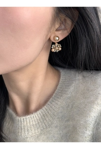 Close-up of model wearing gold flower earrings with small pearls and clear crystals