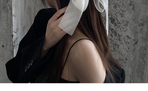 Detail shot of a black tulle bow spring clip on a woman's hair with a black camisole