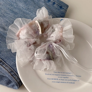 Detail of floral lace scrunchie with a white ribbon bow and Sweety Girl tag on a white plate