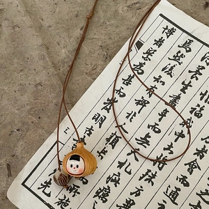 Artistic pendant necklace with wood grain and ceramic doll details on vintage calligraphy paper