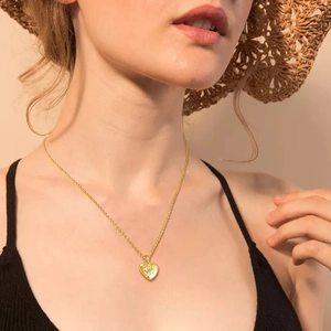 Dettaglio di una collana con ciondolo a cuore dorato con zircone malocchio su modella