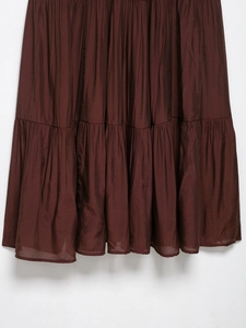 Detailed view of brown tiered skirt layers featuring fine pleated texture and soft fabric