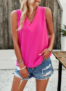 Detail of bright pink V-neck sleeveless top on model with minimalist jewelry
