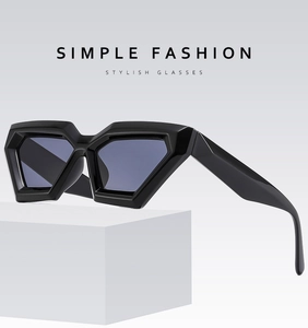 Detail of black geometric polygon sunglasses with glossy finish on a white stand