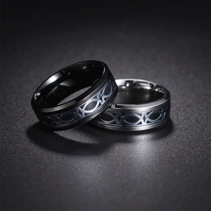 Macro shot of black and silver titanium steel rings with Celtic knot patterns on a dark background
