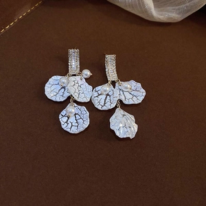 Detailed close-up of pearl and square zircon tassel earrings with white shell petals