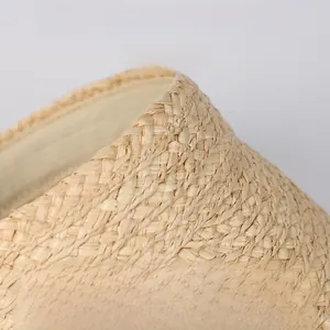 Close-up of hand-woven natural raffia straw sun hat showing fine texture and airy weave