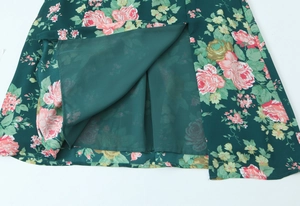 Detail of dark green floral midi dress featuring side slit and soft inner lining