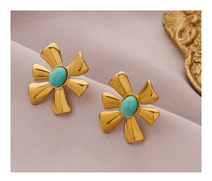Detailed macro view of vintage gold flower earrings with turquoise stone inlay on silk