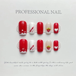 Detail view of handmade red and white press-on nails with strawberry and heart 3D designs