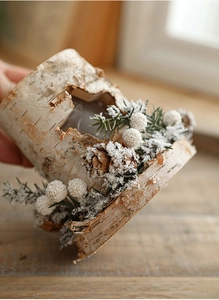 Close-up of birch bark candle holder with pine cones, needles and faux snow detail