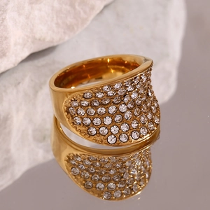 Gros plan d'une bague large concave dorée avec pavage de cristaux étincelants