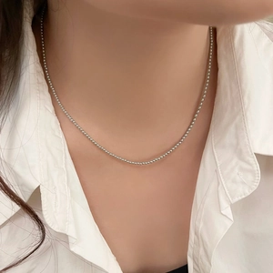 Detail of minimalist 2mm silver bead chain necklace worn with a white shirt collar