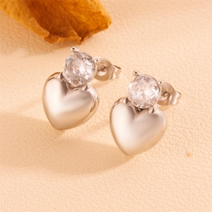 Macro shot of silver heart earrings with sparkling cubic zirconia on beige leather