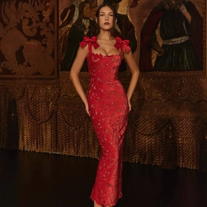 Detailed view of red lace dress featuring shoulder bow tie and elegant floral patterns