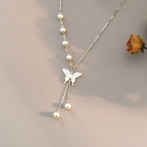 Macro shot of mother-of-pearl butterfly pendant with freshwater pearls on silver chain