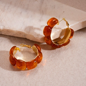 Detailed view of amber resin hoop earrings with gold metal accents on marble