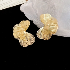 Gros plan détaillé de boucles d'oreilles fleurs dorées ajourées sur fond de velours noir