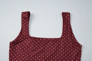 Dettaglio dello scollo quadrato e dei pois bianchi retrò sul tessuto del top rosso
