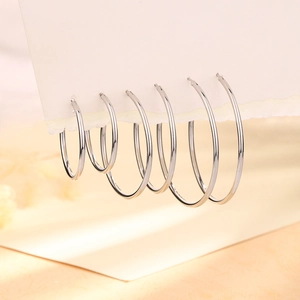 Detailed set of three silver hoop earrings in varying sizes on a minimalist display card