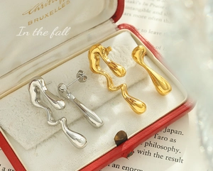 Detalle de pendientes asimétricos en metal fluido dorado y plateado de diseño moderno