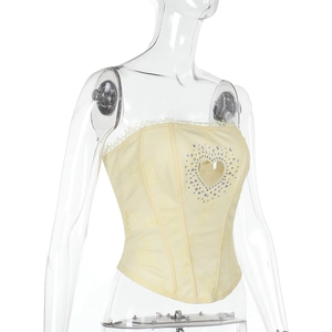 Détail d'un haut corset en dentelle jaune clair avec un cœur ajouré en strass étincelants