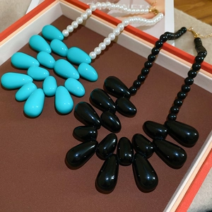 Détail de colliers à pendentif goutte en acrylique bleu et noir avec chaînes perlées
