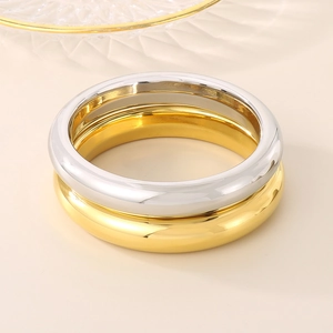 Close-up of minimalist gold and silver hollow round bangles in polished stainless steel