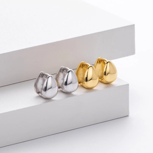 Detailed view of teardrop earrings in gold and silver finish on a white background